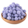 A pile of purple glitter resin beads for jewelry making in a wooden bowl.