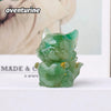 A small, translucent green aventurine crystal sculpture shaped like a fox, used for Feng Shui decor.