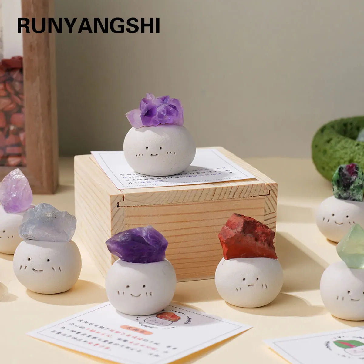 A collection of white bean-shaped decorative stones and a purple crystal on a wooden box.