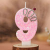 Pink glitter number 9 birthday candle with a crown topper on a white base