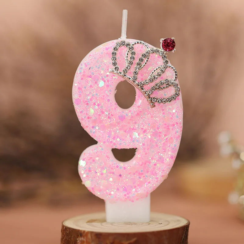 Pink glitter number 9 birthday candle with a crown topper on a white base