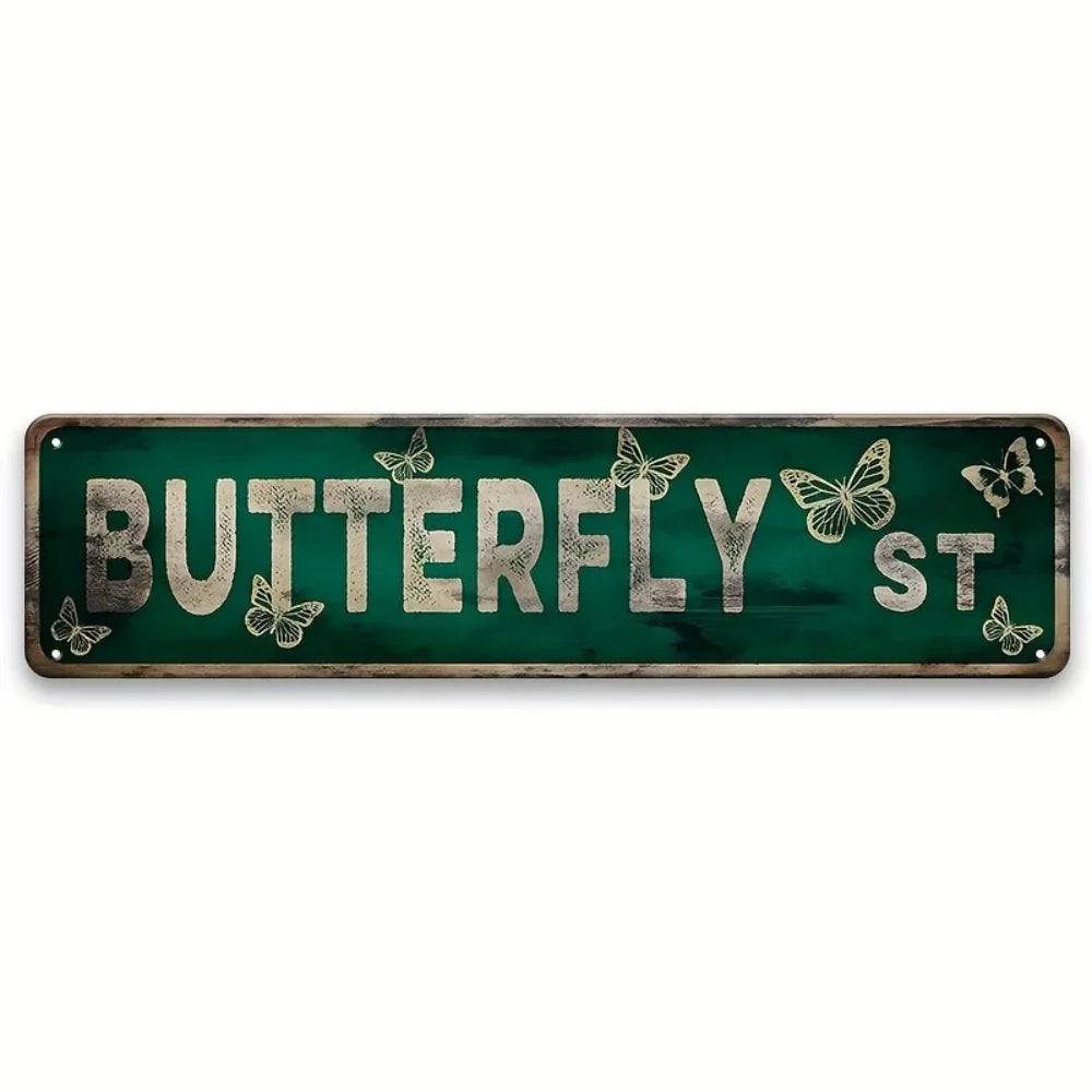 A distressed green metal tin sign with the words BUTTERFLY ST carved into it and decorated with butterflies.