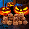 A collection of mini resin pumpkins carved into jack-o'-lantern faces displayed on a dark wooden surface.