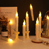 A display of white taper candles and pillar candles lit with a warm glow on a white surface.