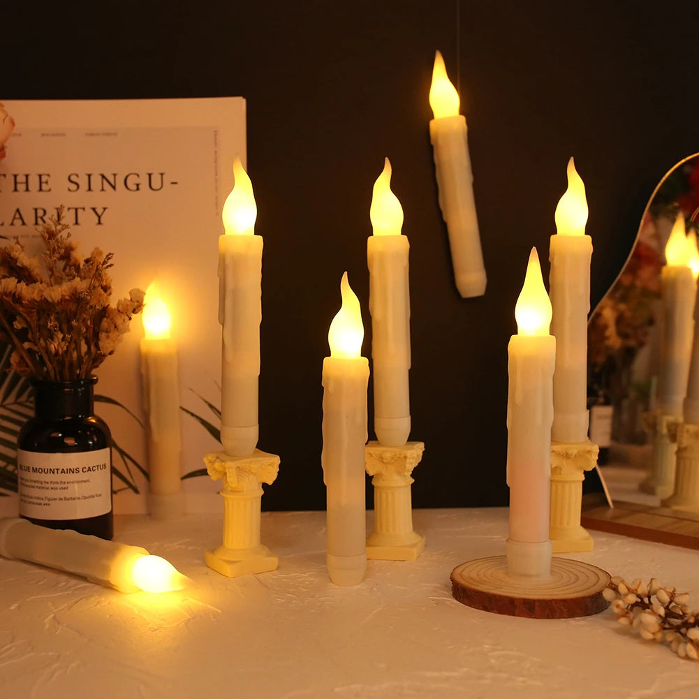 A display of white taper candles and pillar candles lit with a warm glow on a white surface.