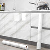 A roll of white marble self-adhesive wallpaper displayed next to kitchen cabinets and a stainless steel pot.