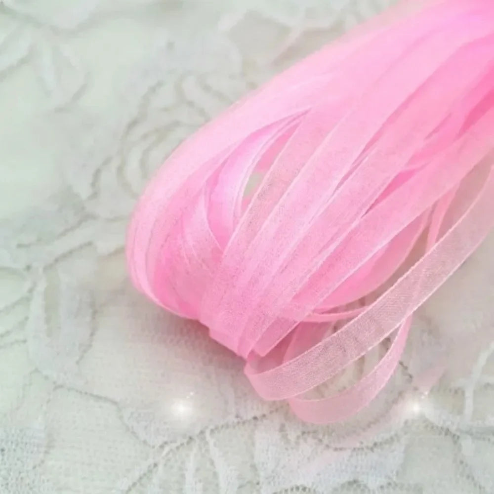 Pink decorative fishtail yarn ribbon coiled on a white surface.