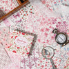 A vintage paper pack featuring pink and red floral patterns, including tissue paper, a magnifying glass, and an antique-style