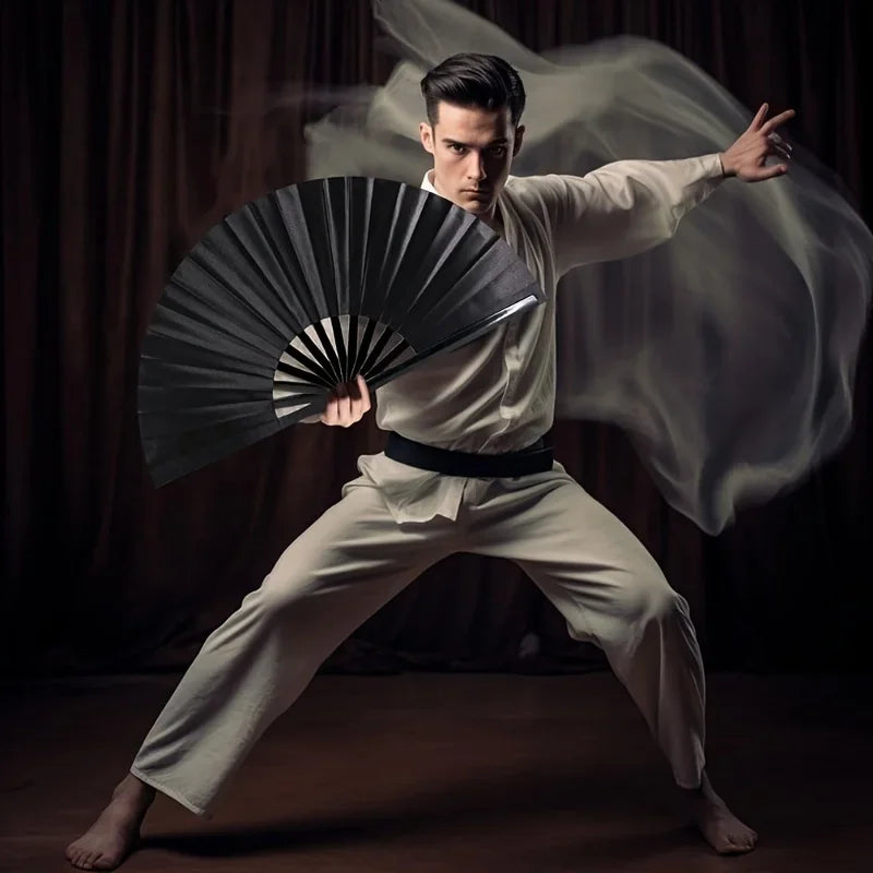 A male model in a white gi performs a martial arts pose while holding a black folding hand fan.