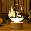 A glowing acrylic night light featuring a silhouette of a deer and trees against a dark background.