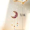 A hanging crystal dreamcatcher featuring a purple moon and dangling prism charms.
