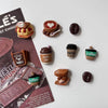 A collection of coffee bean fridge magnets featuring various coffee-themed designs and colors.