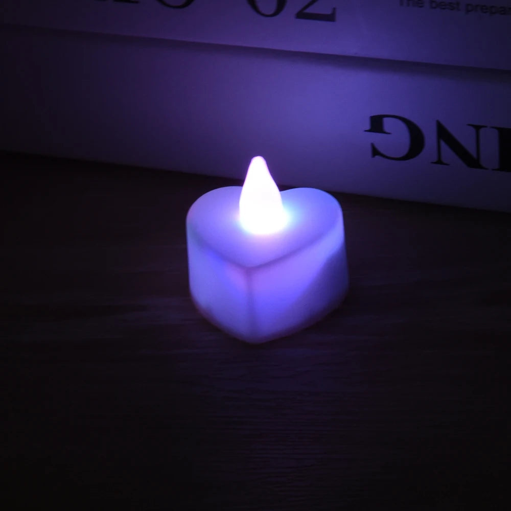 A glowing purple heart-shaped LED tealight candle resting on a dark wooden surface.
