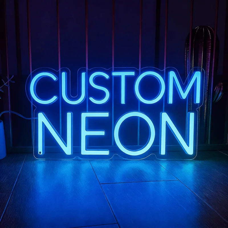A bright blue neon sign spelling out CUSTOM NEON is displayed against a dark background.