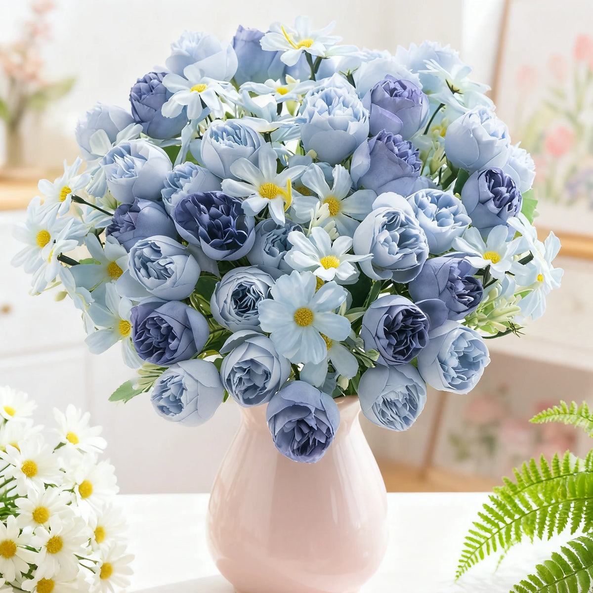 Un ramo de rosas y margaritas artificiales azules y lavanda en un jarrón rosa.