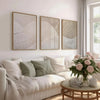A set of three framed abstract canvas prints featuring beige and white textured mountain landscapes on a white wall.