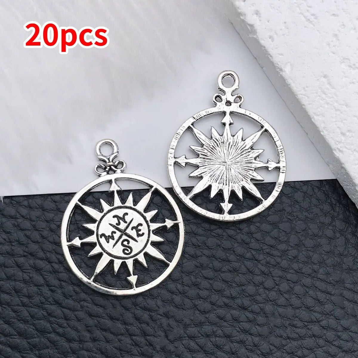 20 pieces of silver vintage ship anchor charms for jewelry making displayed on a dark surface.