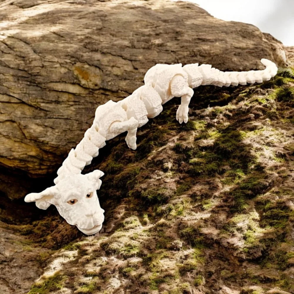 Figurine de dragon peinte à la main, blanche et réaliste, sur une roche moussue.