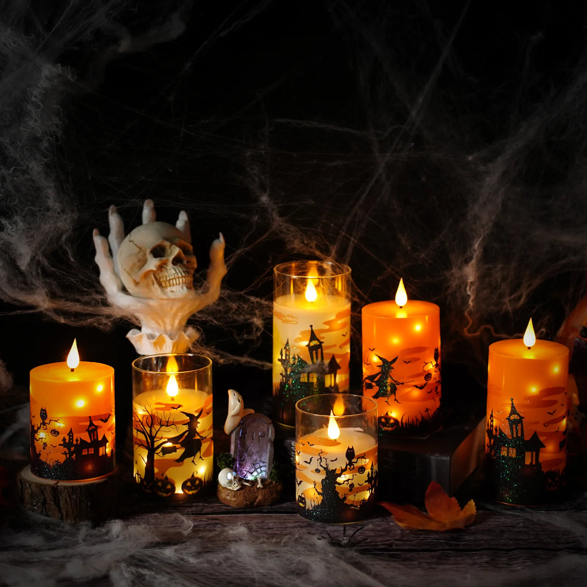 A collection of glowing pillar candles and a skull decoration set against a dark, smoky background for Halloween decor.