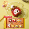 A collection of six cute, round squeeze toys or keychains in various colors and designs are displayed on a light orange tray.