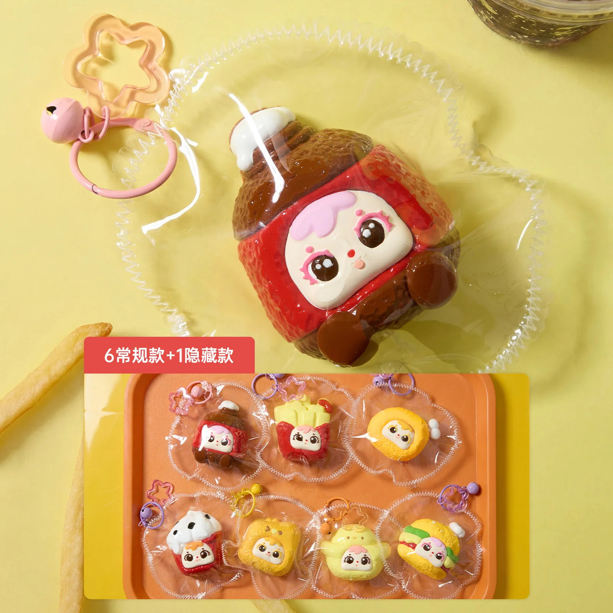 A collection of six cute, round squeeze toys or keychains in various colors and designs are displayed on a light orange tray.