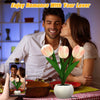 A couple is shown embracing while a potted LED tulip night light sits on a table.