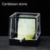 A clear glass box containing a pale green Caribbean stone specimen.