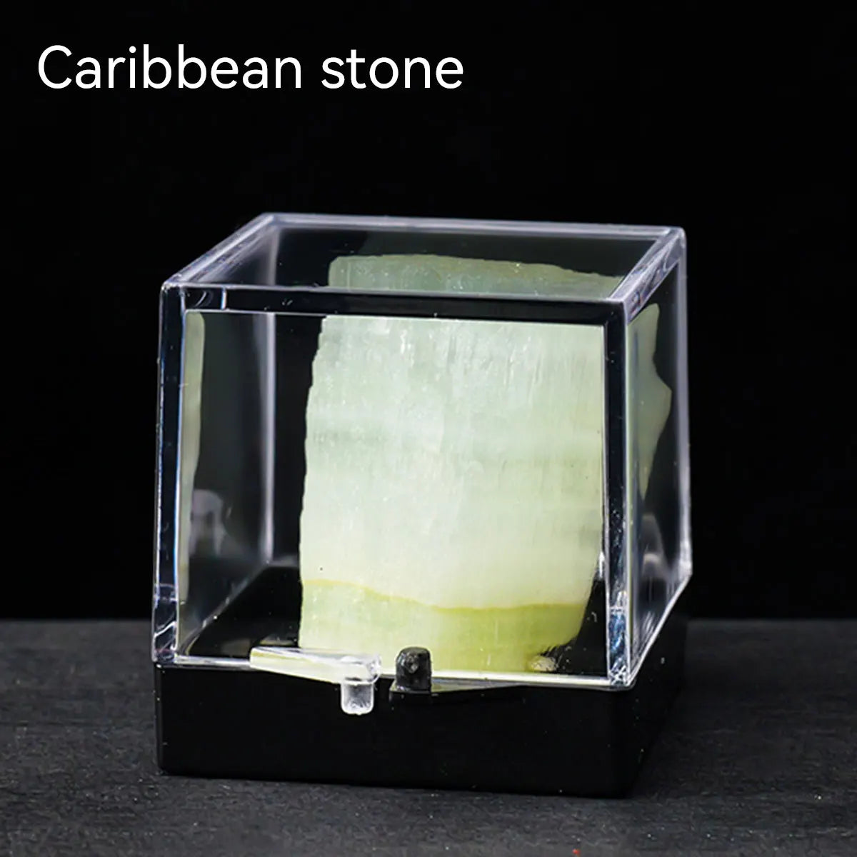 A clear glass box containing a pale green Caribbean stone specimen.