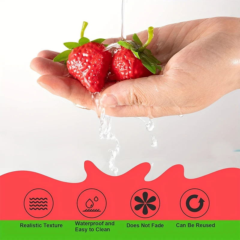 A hand is holding artificial strawberries that are dripping water, demonstrating a realistic texture and waterproof quality.
