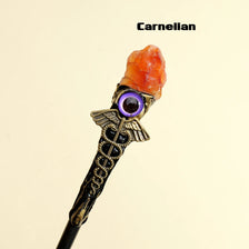 A dark wand with a rose quartz and amethyst evil eye crystal head.