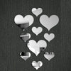 A collection of white 3D acrylic heart mirror wall stickers scattered against a dark background.