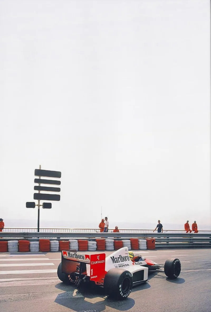 A red and white Formula 1 race car is driving on a track, with a safety barrier in the foreground.