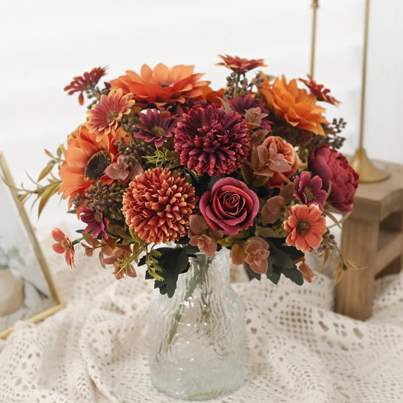 A bouquet of silk autumn roses and hydrangea flowers in warm tones of orange, pink, and deep red.