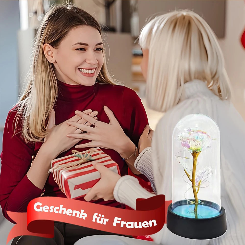 Une femme en haut rouge offre une rose en verre avec une lumière LED à une autre femme.