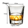 A clear whiskey glass with a thick base and a tapered rim, showing a golden amber liquid.