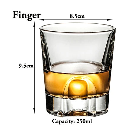 A clear whiskey glass with a thick base and a tapered rim, showing a golden amber liquid.