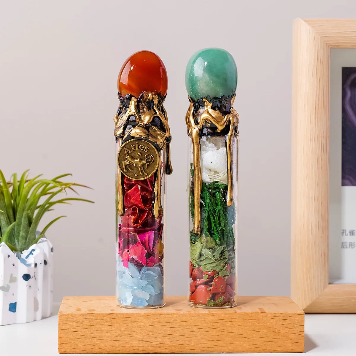 Two glass bottles filled with natural crystal and healing stones, featuring gold accents, displayed on a wooden surface.
