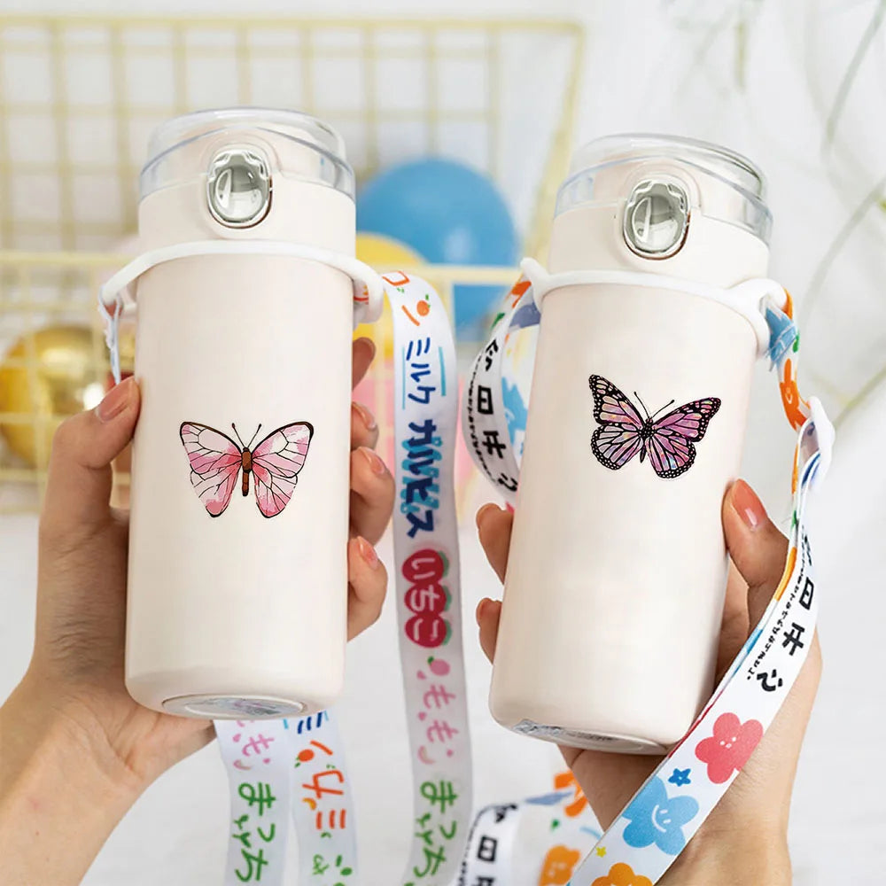 Des mains tiennent une bouteille en plastique rose clair avec un autocollant de papillon et un ruban coloré.