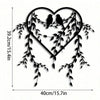 Black metal wall decor featuring a heart shape adorned with vines and two birds