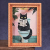 A framed watercolor portrait of a black cat sitting on a toilet, displayed in a wooden frame.