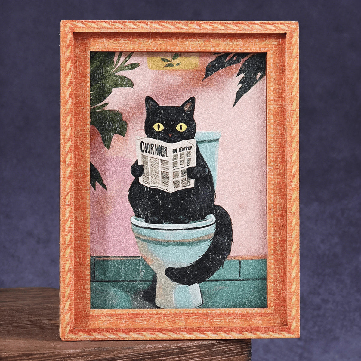 A framed watercolor portrait of a black cat sitting on a toilet, displayed in a wooden frame.