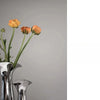 A silver-plated ceramic vase holds stems with orange and yellow flowers against a gray background.