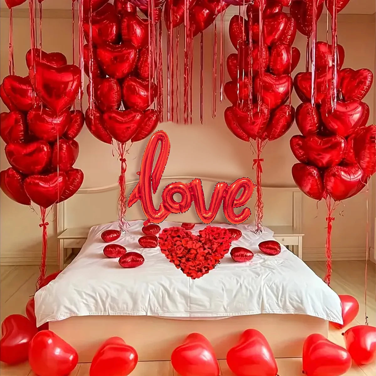 Eine Anordnung roter herzförmiger Ballons, die von einer Decke herabhängen und um ein Bett herum angeordnet sind.