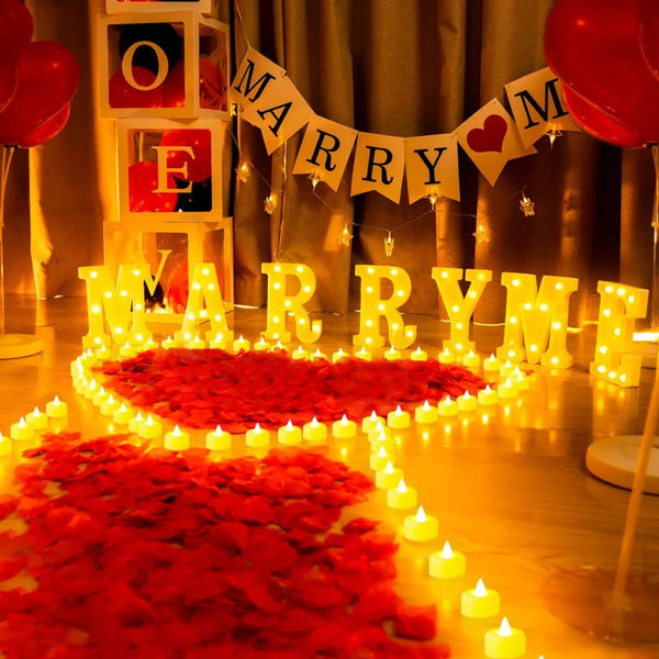 Une décoration festive avec des lettres lumineuses 'MARRY ME' entourées de pétales de roses rouges.