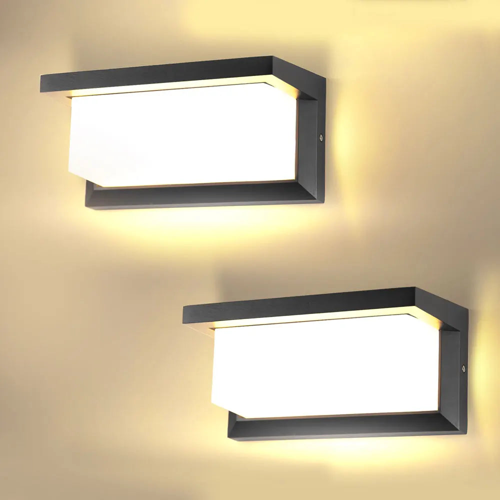 A modern black rectangular LED wall sconce with a bright white light mounted on a beige wall.
