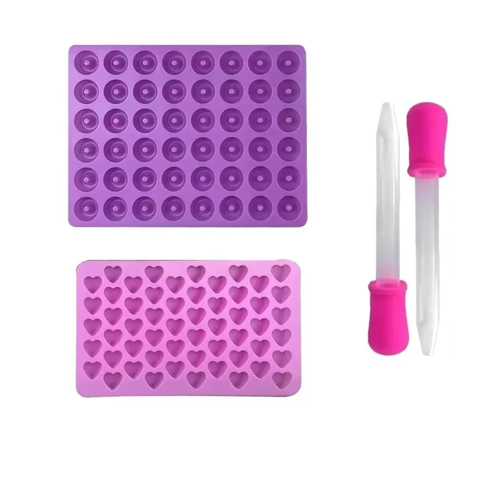 A set of purple silicone candy molds with pink droppers for DIY chocolates and jellies