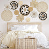 A collection of woven straw wall hangings and tassels arranged above a bed.