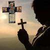 Silhouette of a person holding a handcrafted pocket shrine with a cross against a sunset sky.