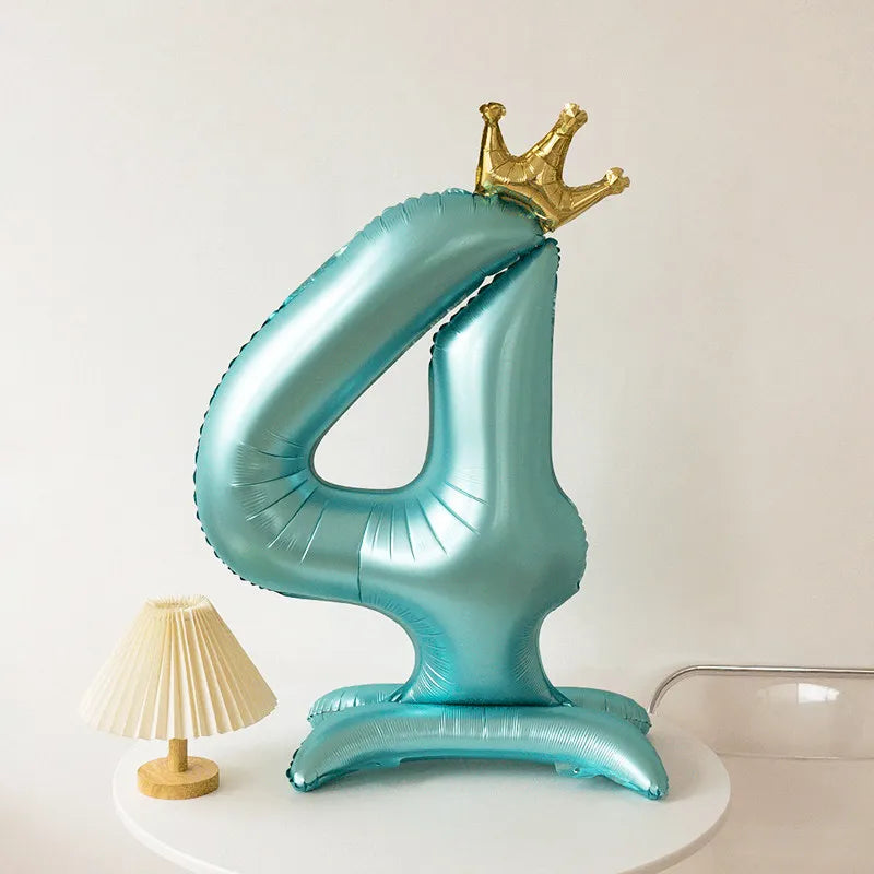 A large, light blue foil balloon shaped like the number four with a gold crown on top.