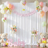 A pink and white fabric backdrop for a baby shower featuring floral arrangements and a large pink baby text